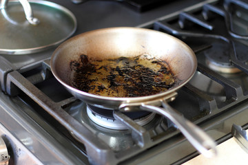 Leftover grease and char on a stainless steel pan after cooking.