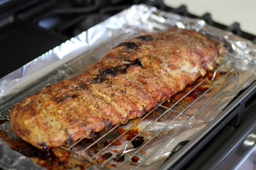 Rack of St. Louis cut style ribs resting in a baking tray on the stove top.