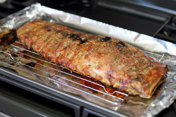 Rack of St. Louis cut style ribs resting in a baking tray on the stove top.