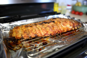 Rack of St. Louis cut style ribs resting in a baking tray on the stove top.