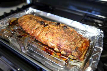 Rack of St. Louis cut style ribs resting in a baking tray on the stove top.