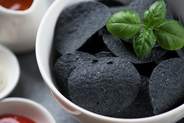 Fototapeta premium Close-up of black potato chips in a bowl, selective focus, horizontal shot