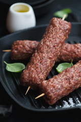 Closeup of fresh uncooked marbled beef kabobs on wooden skewers, vertical shot