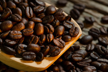 Close up the coffee seeds in the wooden spoon with warm tone temperature