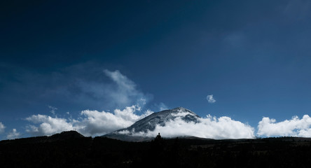 Popocatepetl mexican volcano surrounded by clouds in a cold and sunny day of winter