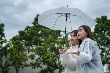 happy, relaxed women with raincoat and umbrella in cloudy, overcast day; pleasant rainy weather