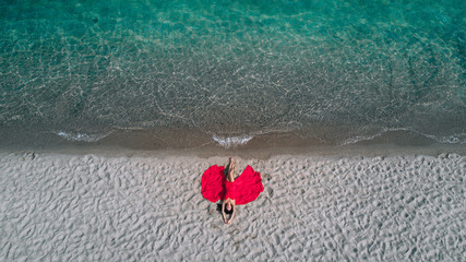 Fototapeta na wymiar Aerial view of passionate woman in a red dress lying on the seashore. Phuket. Thailand