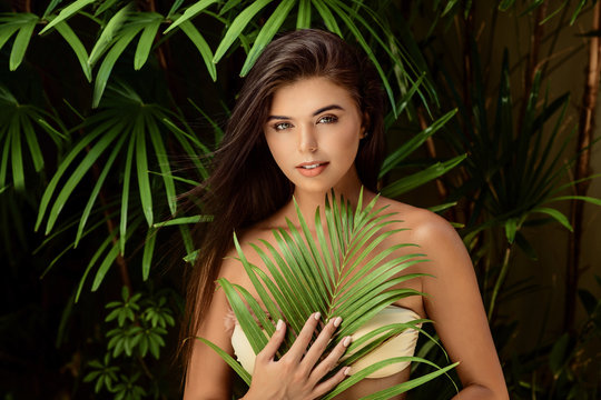 young smiling brunette woman with big green leaf on nature background , spa care people concept close up .
