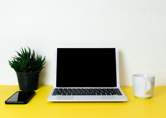 Laptop placed on a yellow table background of business working place with cup coffee, Empty workspace