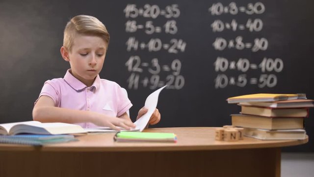 Irritated schoolboy tearing page from notebook, unable to solve difficult task