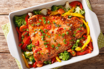 Red fish fillet baked with vegetables, spices and herbs close-up in a baking dish. Horizontal top...