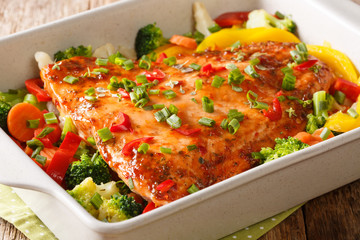 Red fish fillet baked with vegetables, spices and herbs close-up in a baking dish. horizontal