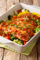 Spicy baked salmon fillet with vegetables and herbs close-up in a baking dish. vertical