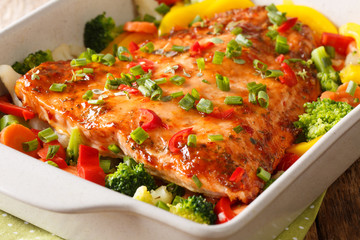 baked salmon with summer vegetables close-up in a baking dish. horizontal