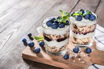 Yogurt with granola and fresh blueberries on rustic background