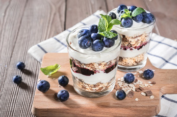 Yogurt with granola and fresh blueberries on rustic background