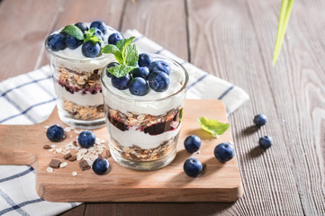 Yogurt with granola and fresh blueberries on rustic background