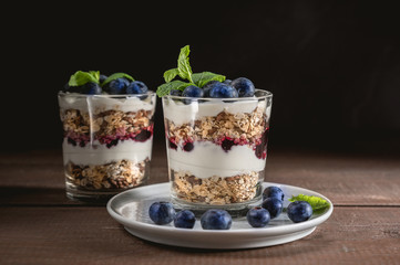 Yogurt with granola and fresh blueberries on rustic background