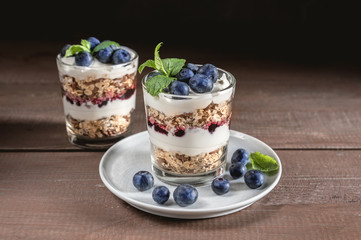 Yogurt with granola and fresh blueberries on rustic background