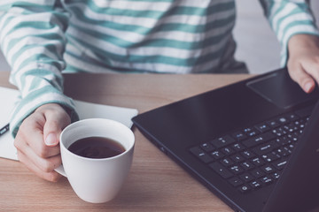Cup of coffee with businesswoman working with laptop on desk office.vintage tone.