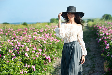 Beautiful girl in straw hat collect roses in Bulgaria in sunrise. Series.