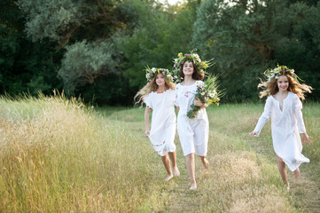 Naklejka premium Three girls with wreaths of flowers in their hands. Midsummer. Earth Day.