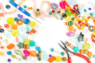 Many different beads with tools for making jewellery, shot from the top on a white background with a place for text