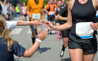 Marathon running race,runners support on road race, child's hand giving highfive, kid supporting...