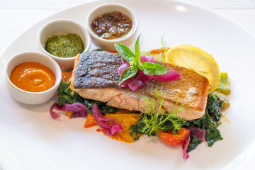 close up of grilled pan seared salmon fillet whit vegetables and sauce italian style