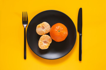 Tangerines in black plate on yellow