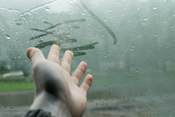 the human hand fingers drawing lines on a sweaty moisture from the inside glass of the car in rainy...