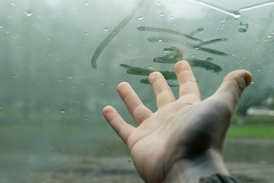 The Human Hand Fingers Drawing Lines On A Sweaty Moisture From The Inside Glass Of The Car In Rainy Weather