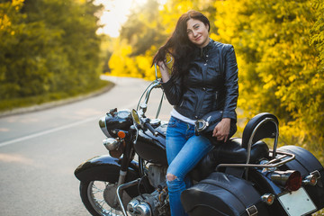 Obraz na płótnie Canvas attractive brunette motorcyclist sits on a motorcycle. adventure concept