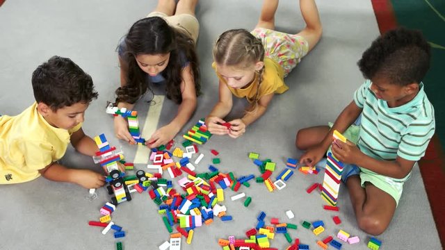 Kids playing with block toys, top view. Group of children playing together in the classroom in preschool. Kids activity and fun.