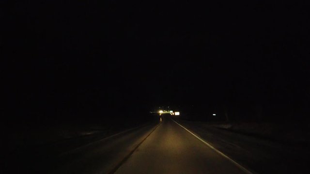 Driving On Road At Night With Oncoming Traffic Bright Headlights And Roundabout Traffic Signs