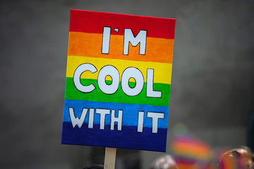 Rainbow flag sign with words supporting LGBT community on gay parade event. Colourful flag banner during gay pride celebration