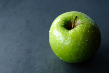 Big fresh green apple with drops of water at the black background