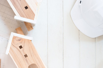 Obraz na płótnie Canvas Miniature house model with blueprint plan, white safety helmet on white wood background, copy space