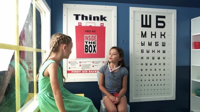 Beautiful girl playing oculist at medical office. Two little girls playing doctor and patient. Ophthalmology, eye doctors office.