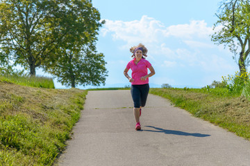 Fit middle-aged woman jogging on a country road