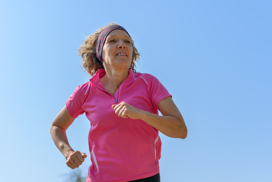 Fit middle-aged woman jogging in spring sunshine