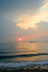 Beautiful cloudy sunset and sea landscape. Pink and gold colored sky in the evening.
