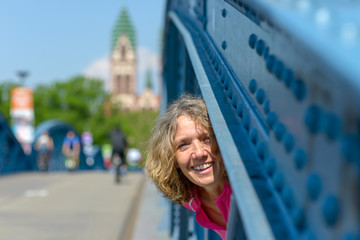 Playful laughing woman peering through a bridge