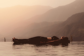 Morning light with Beautiful Attractive Asian woman practice yoga Dead Body or Savasana on the pool...