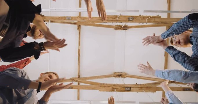 Low Angle Close-up, Happy Group Of Diverse Business People Put Hands Together. Teamwork At Modern Loft Office Background