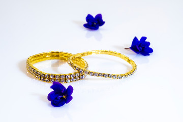 Two brilliant metallic gold bracelets and blue flowers.