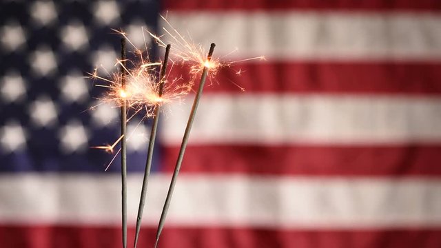 Sparkler Closeup With American Flag In Background. Celebrating 4th Of July Independence Day