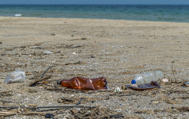 Fototapeta na wymiar Conceptual: Disaster, Environmental problem - plastic trash. Spilled garbage on the beach of big city. Empty used dirty plastic bottles. Dirty sea, sandy coast of Black Sea. Environmental pollution