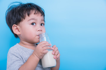 Asian little child boy about 2 year drinking milk from bottle glass itself