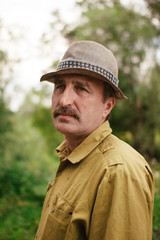 An elderly man travels with a suitcase. A sad and tired villager is on the road to a long way.